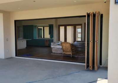 A modern home features a large open doorway with folding doors, leading to an unpacked living area with a vintage chair and unfinished decor.