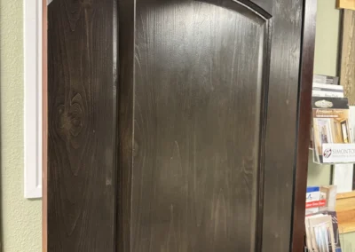 A close-up of a dark, wooden door from the Knotty Alder Series, showcasing its sleek design and textural detail.